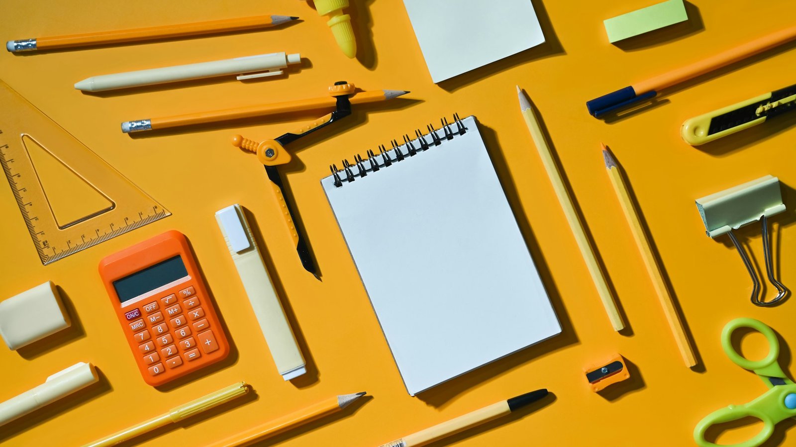 Blank notepad and various school supplies on yellow background. Flat lay, Top view.