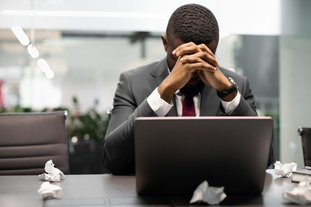 Tired black manager suffering from burnout, working on laptop