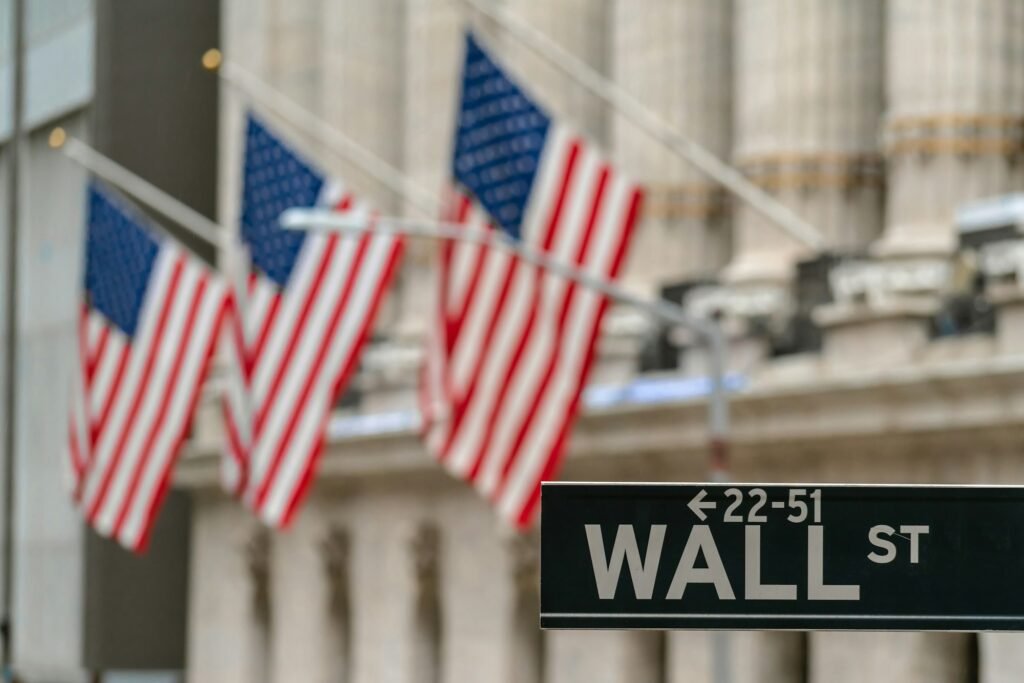 Wall Street "WALL ST" sign and broadway street over American national flags