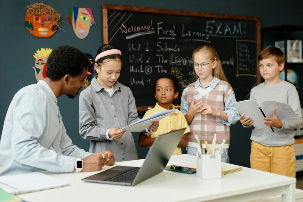 Diverse group of Students Showing Copybooks with Homework to Teacher in Classroom