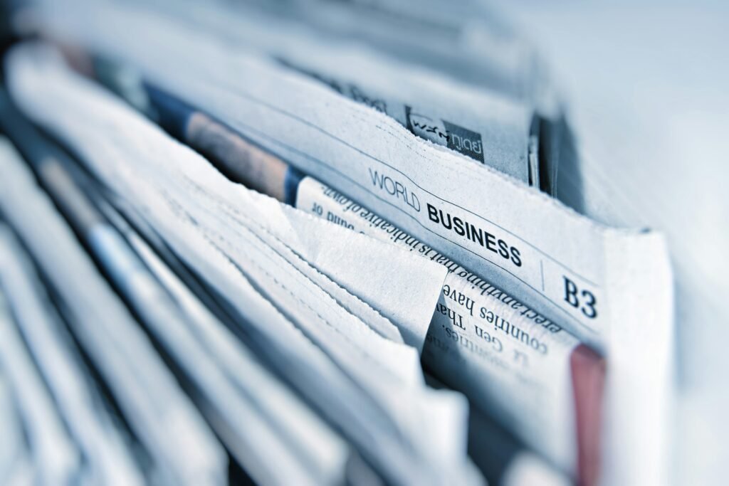 Close-up of folded newspapers featuring a business section headline, symbolizing the role of media literacy in analyzing news sources and current events.