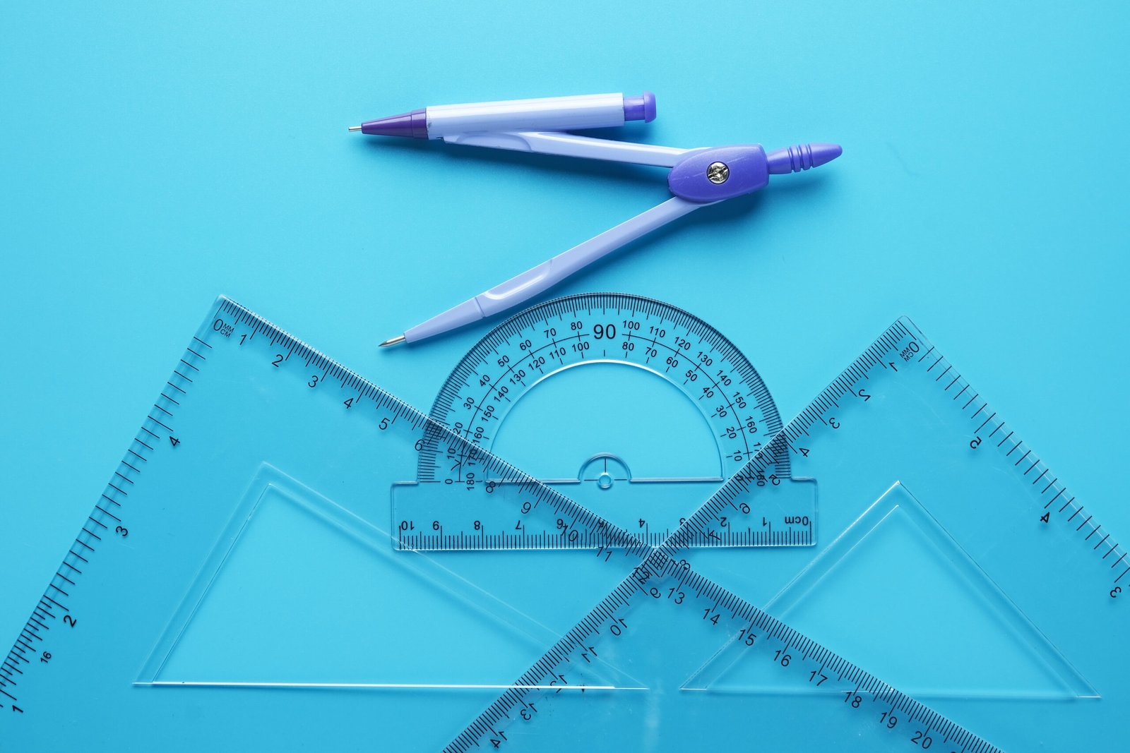 Compass, protractor, and rulers on a blue surface