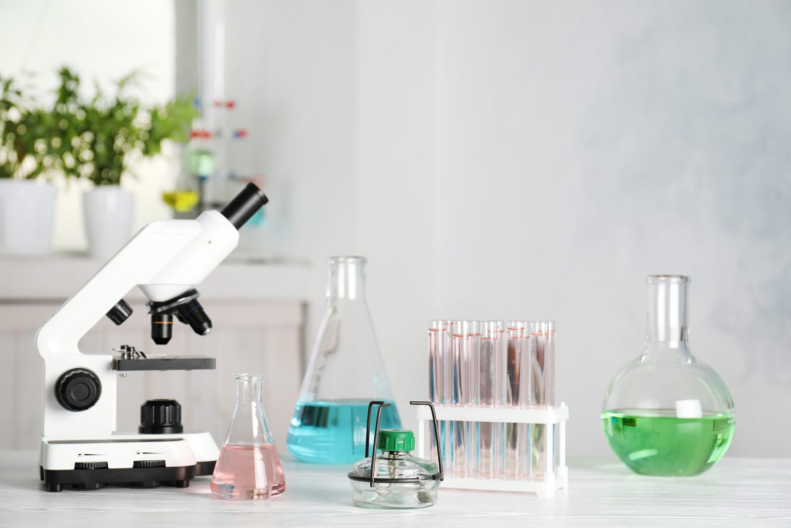 Microscope and laboratory glassware on a bright science bench