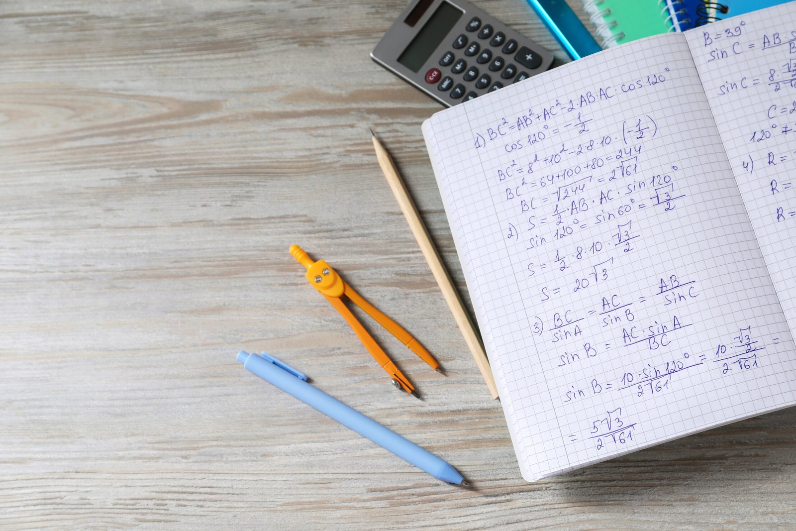 An open mathematics notebook beside stationery