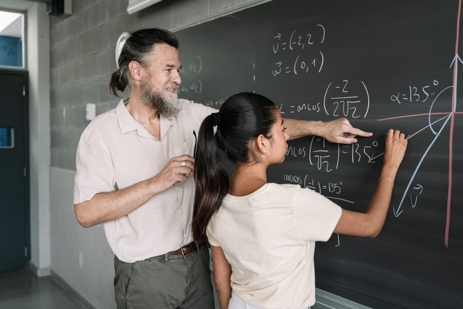 A student and teacher working through mathematics at a chalkboard