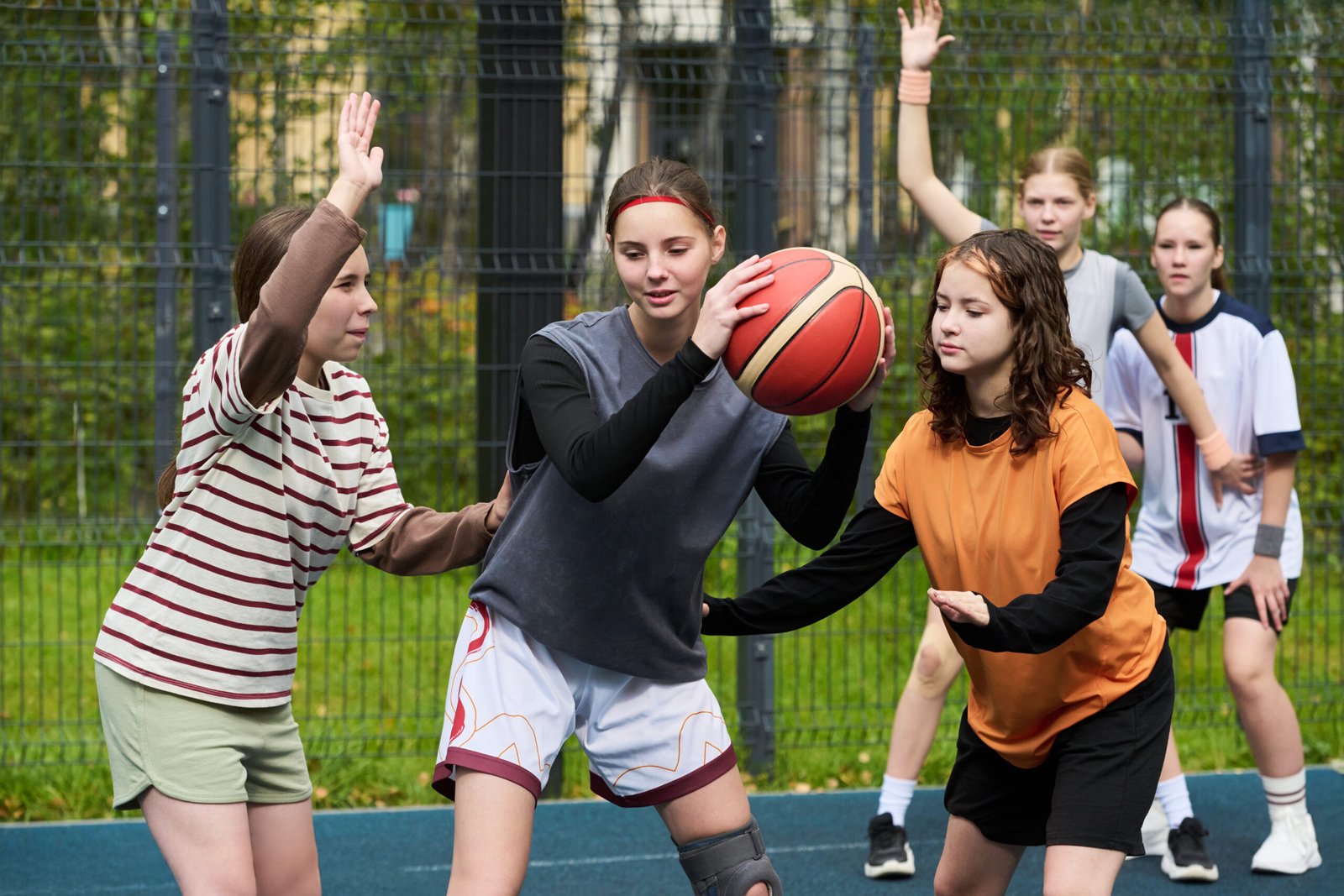 Teenagers playing basketball together on an outdoor court